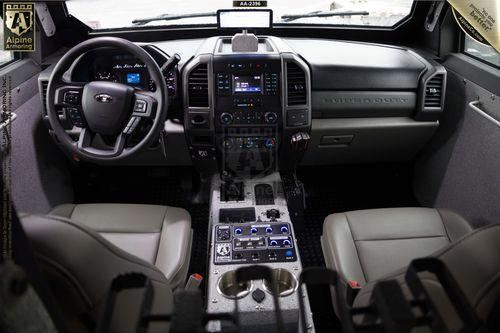 Interior of a Pit-Bull VX showing the steering wheel, dashboard with various controls and displays, center console with cup holders and additional buttons, and two front seats.