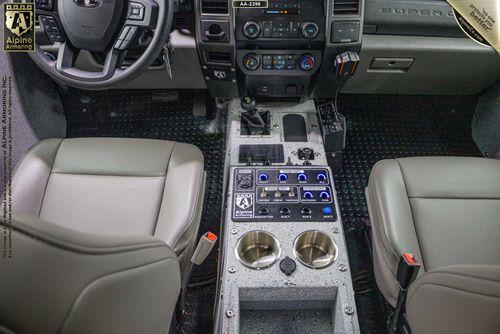 Interior of a Pit-Bull VX featuring beige seats, a control panel with switches, two cup holders in the center console, and dashboard instruments.