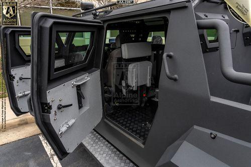 Open interior of a black armored black Pit-Bull VXT with a side door ajar, showcasing seating and equipment inside.