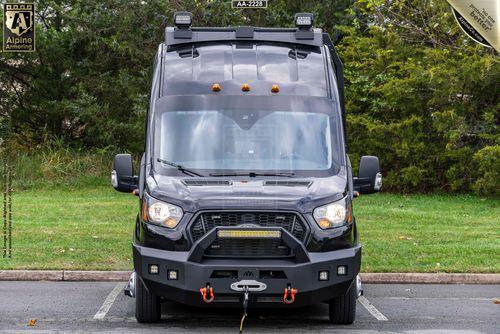 Front view of a black off-road equipped Pointer Van with a winch and other attachments, parked in an outdoor setting with trees in the background.