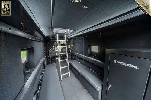 Interior of a secure Ford Transit Pointer Van with a ladder, seating benches, and storage compartments, showcasing an organized and functional setup.