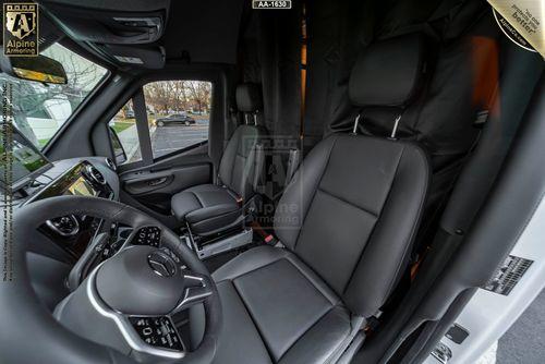 Interior of an armored SWAT Van - Pointer featuring the driver's seat and passenger seat with black leather upholstery, a steering wheel, dashboard, and a black partition curtain behind the seats.