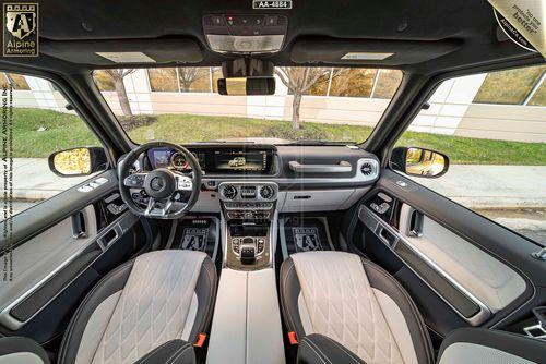 Interior view of a armored Mercedes-Benz G63 AMG featuring a modern dashboard with a large touchscreen display, a multi-function steering wheel, and two-tone leather seats.