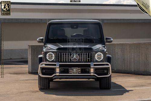 Front view of a black Mercedes-Benz G-Class SUV, from Alpine Armoring,  parked in an outdoor parking area.