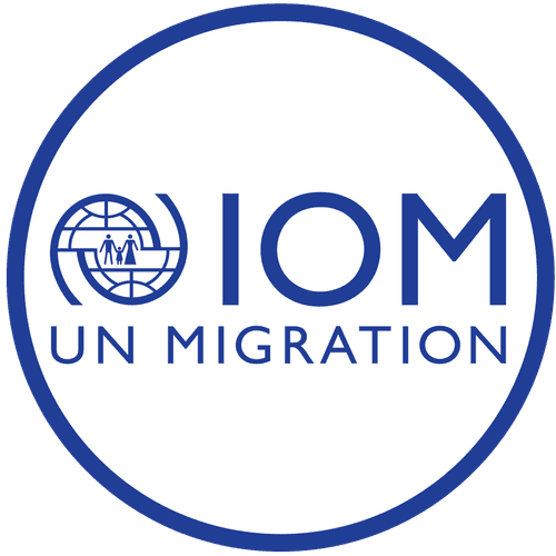 IOM UN Migration logo with blue text and a circular emblem featuring a globe and silhouettes of two people walking, all enclosed in a blue-bordered circle.