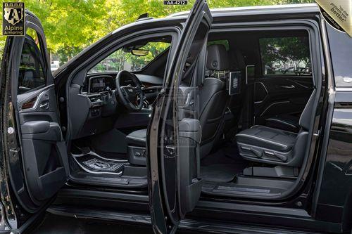 The interior of a black Escalade ESV SUV with its front and rear doors open, revealing leather seats and an equipped dashboard.