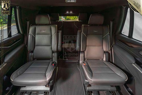 Interior view of a bulletproof Cadillac Escalade Premium Luxury equipped with black leather seats and armrests, arranged to face each other for a comfortable seating arrangement.