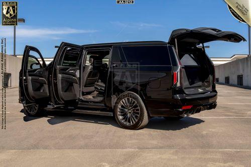 A black armored Cadillac Escalade ESV SUV is parked with all doors and the trunk open on a rooftop parking lot. The vehicle features tinted windows and alloy wheels.